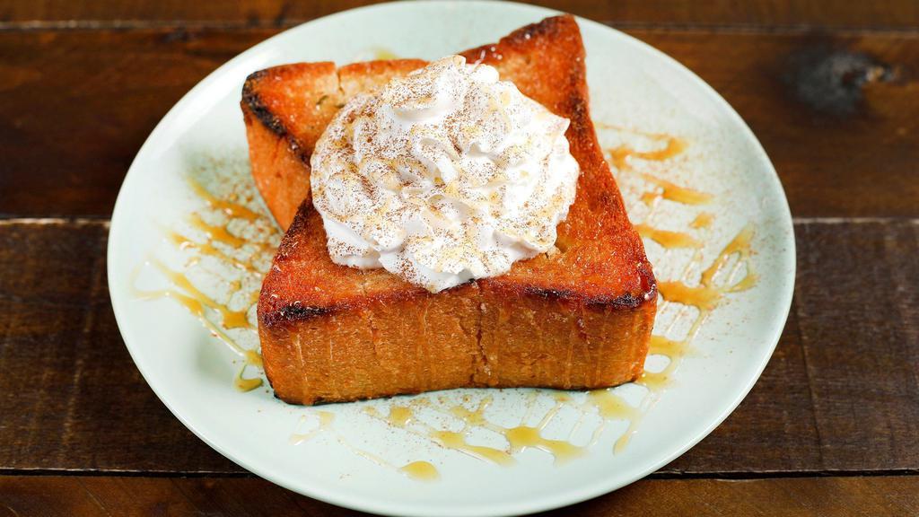Caramel Cinnamon Bread · Brick styled bread topped with powdered sugar, whipped cream, caramel sauce, and cinnamon powder.