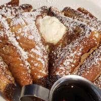 French Toast. · Three toasts are pan fried to a golden brown and served with syrup and butter.