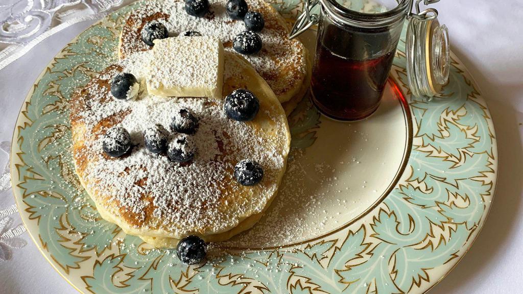 Blueberry Pancakes · 2 large buttermilk blueberry pancakes with syrup and butter.