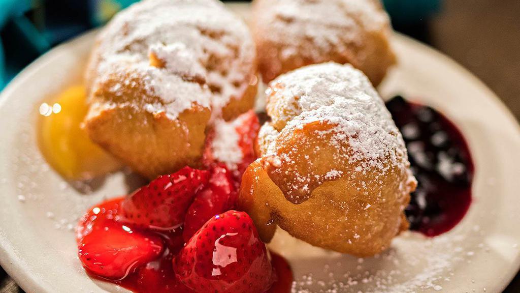 Mardi Gras Beignets · Our signature southern fritters atop sweet, vanilla cream filling with huckleberry. strawberry & peach fruit topping- dusted with powdered sugar.