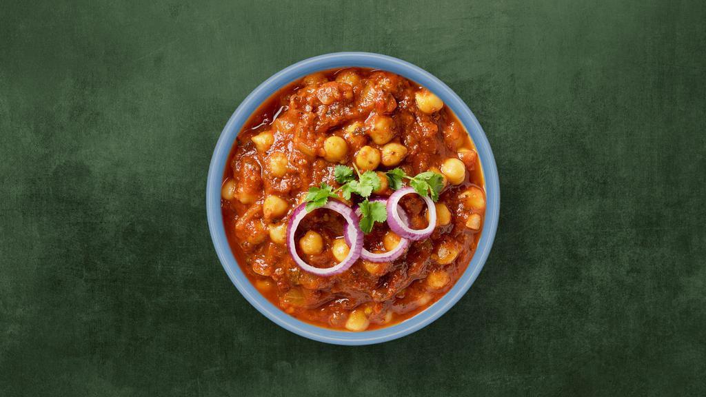 Spiced Chickpea Curry · Chickpeas slow cooked in a thick gravy made of chopped onions, tomatoes, and whole warm spices. Served with a side of plain rice.