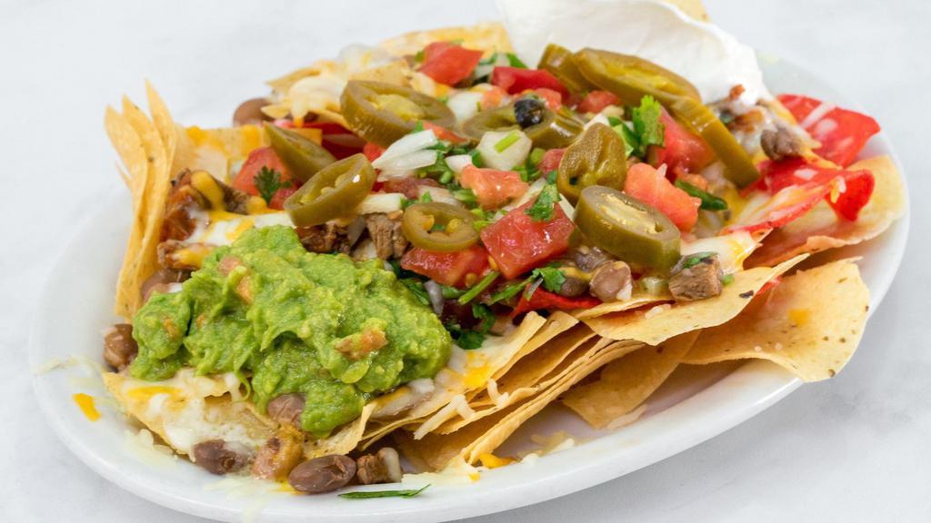 Super Nachos · Chips topped with beans, melted cheese, choice of meat, sour cream, guacamole, salsa fresca and jalapenos.