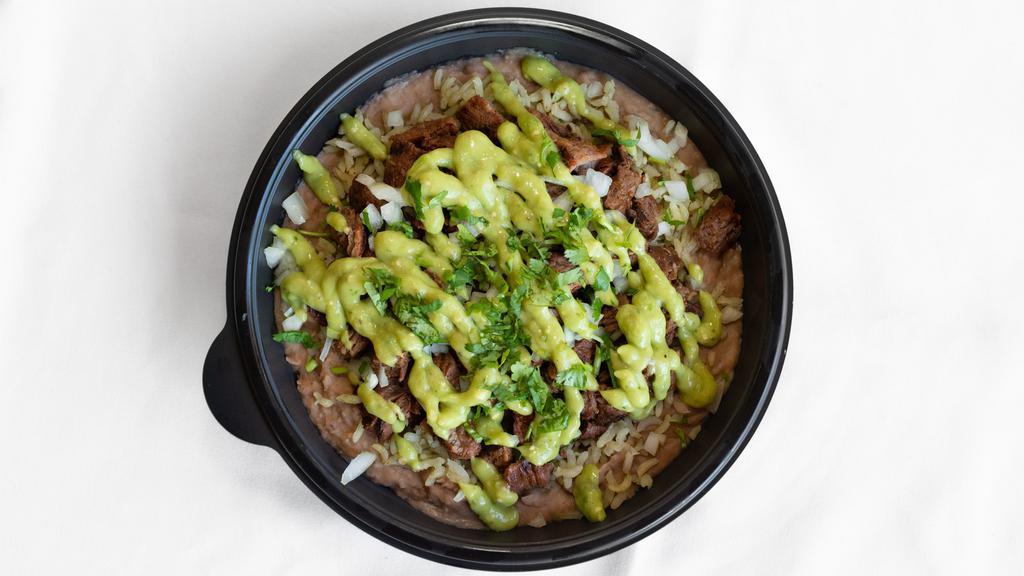 Carne Asada Tazon · a bowl filled with grilled steak, black or pinto beans, rice, onions, cilantro, guacamole and salsa.