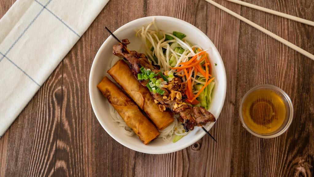 Bun Cha Gio Thit Nuong · Crispy egg roll and BBQ pork/chicken/beef or shrimp over rice noodle, minced cucumber, lettuce, and mint leaves. Topped with roasted peanuts and served with chili lime sauce.