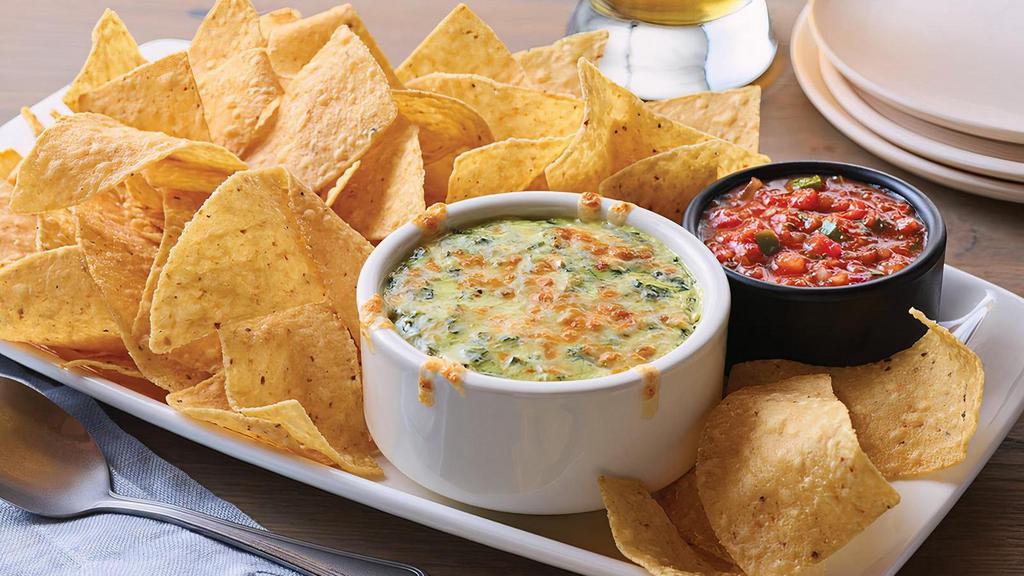 Spinach & Artichoke Dip · Creamy spinach and artichoke dip topped with Parmesan cheese.  Served with freshly made white corn tortilla chips and our chipotle lime salsa.