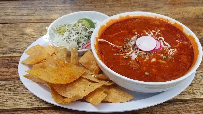 Pozole · Hominy pork stew from Jalisco in a chili broth pepper base, served with cabbage, radish, onions, oregano, lime and corn chips