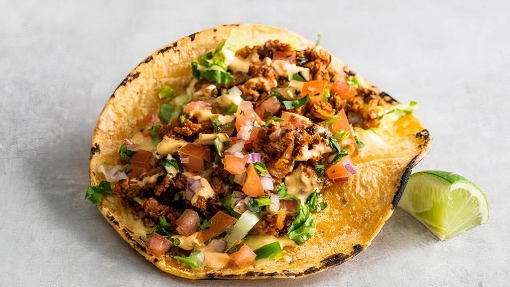 Tejano Style Taco · Impossible ™ tex-mex style taco meat,  topped with queso sauce, shredded lettuce, cilantro, pico de gallo, and Cholula crema and a lime wedge. | Gluten-friendly | 300 cals