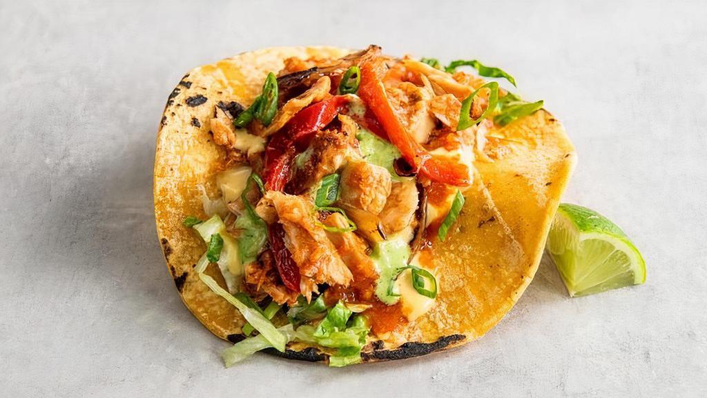 Chickin' Tinga Taco  · Shredded chickin’, grilled onions, red bell peppers in a spicy roja sauce, topped with shredded lettuce, pico, queso sauce, green onions, and baja sauce and a lime wedge. Gluten-friendly. | 300 cals.