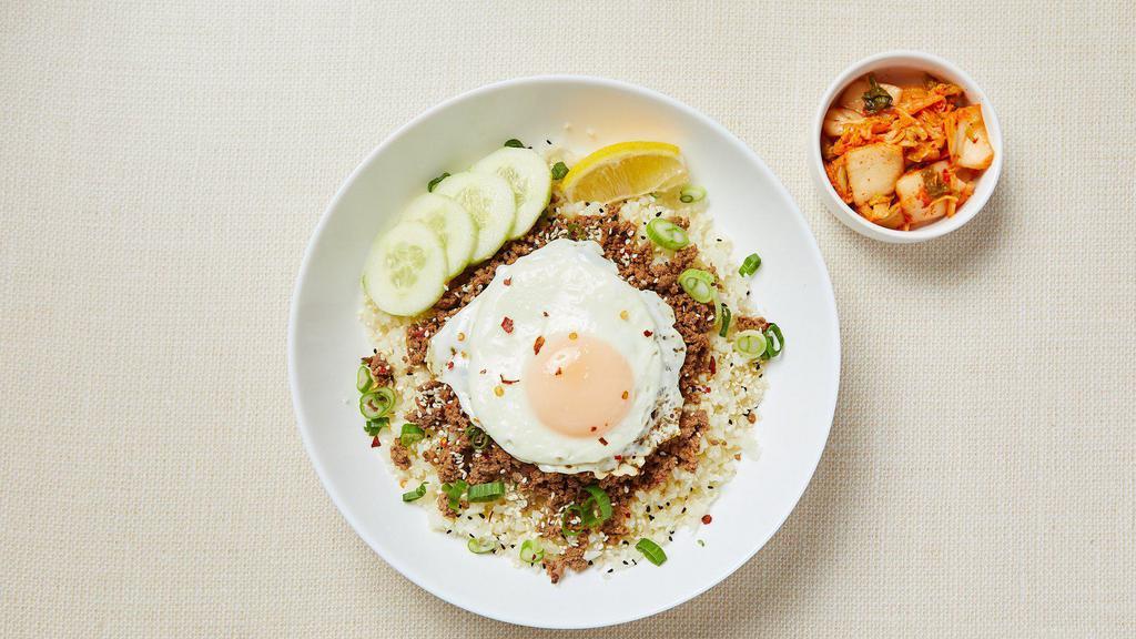 Keto Korean Ground Beef Bowl · Cauliflower rice, spicy ground beef cooked with low-carb soy sauce and sesame oil, served with fried egg, sesame seeds, green onions, cucumber slices, lemon wedge, and kimchi. Gluten-free. Dairy-free.