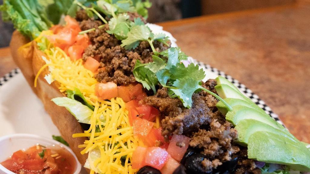 Taco Salad · Your choice of seasoned ground beef or marinated grilled chicken breast served in a crispy tostada bowl lined with refried beans then topped with salad mix, tomato, onion, olive, cheddar cheese, jack cheese, salsa, pickled jalapeño, avocado, cilantro & dressing of your choice.