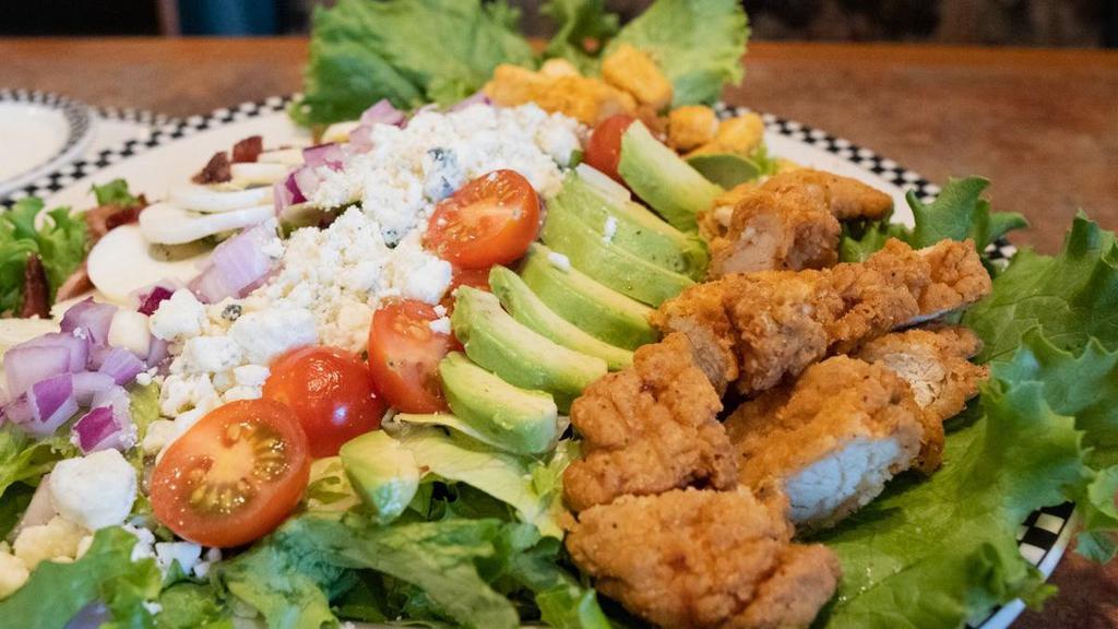 Crispy Chicken Cobb Salad · Salad mix topped with chopped crispy chicken tenders, cherry tomato, crispy bacon, hard-boiled egg, diced avocado, bleu cheese crumbles, red onion & croutons.  Served with your choice of dressing.