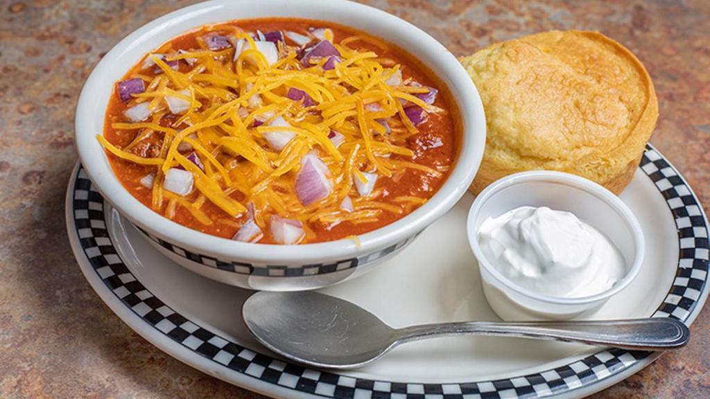 Bowl Of Chili · A red chili that includes pinto beans, ground beef, our housemade Mild Italian sausage, tomato sauce and several other spices!   . Topped with cheddar cheese, diced red onion and served with sour cream and a cornbread muffin.
