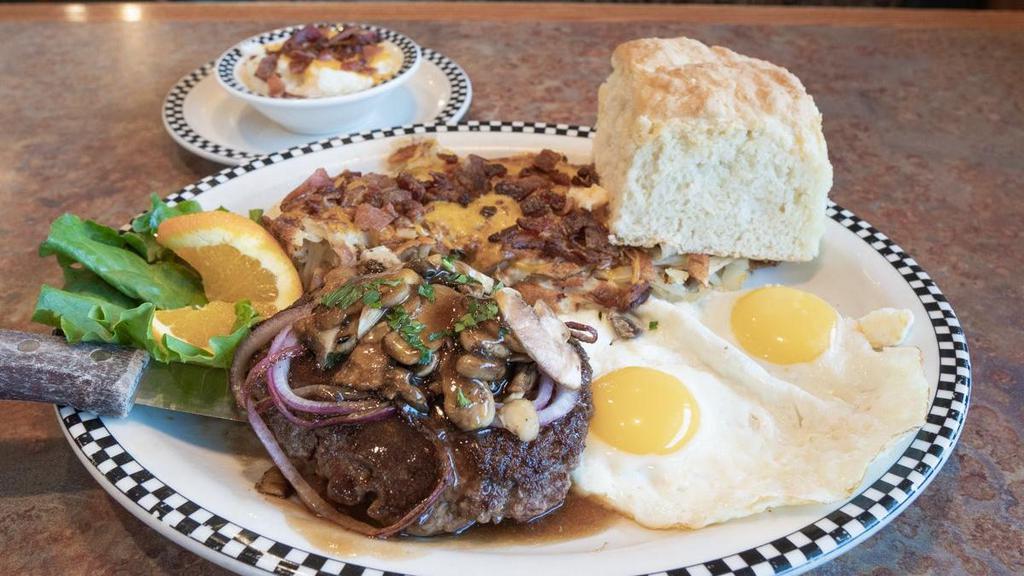 Chopped Steak & Eggs · 10 oz seasoned all-beef patty, topped with sauteed mushrooms & onion in beef gravy.  Served with cheesy bacon grits, 2 eggs any style, your choice of strip-cut hashbrowns OR country red potatoes and your choice of housemade biscuit OR cornbread muffin.