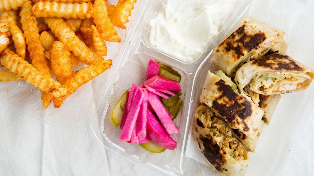 Jordanian Wrap · Chicken shawarma wrap with lavash bread and garlic sauce. On the side are tomatoes, pickles, and fries.