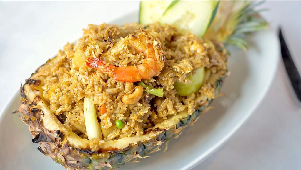 Pineapple Fried Rice · Chicken, prawns, eggs, carrots, peas, onions, scallions, tomatoes, raisins, cashew nuts and pineapple, served in a pineapple shell.