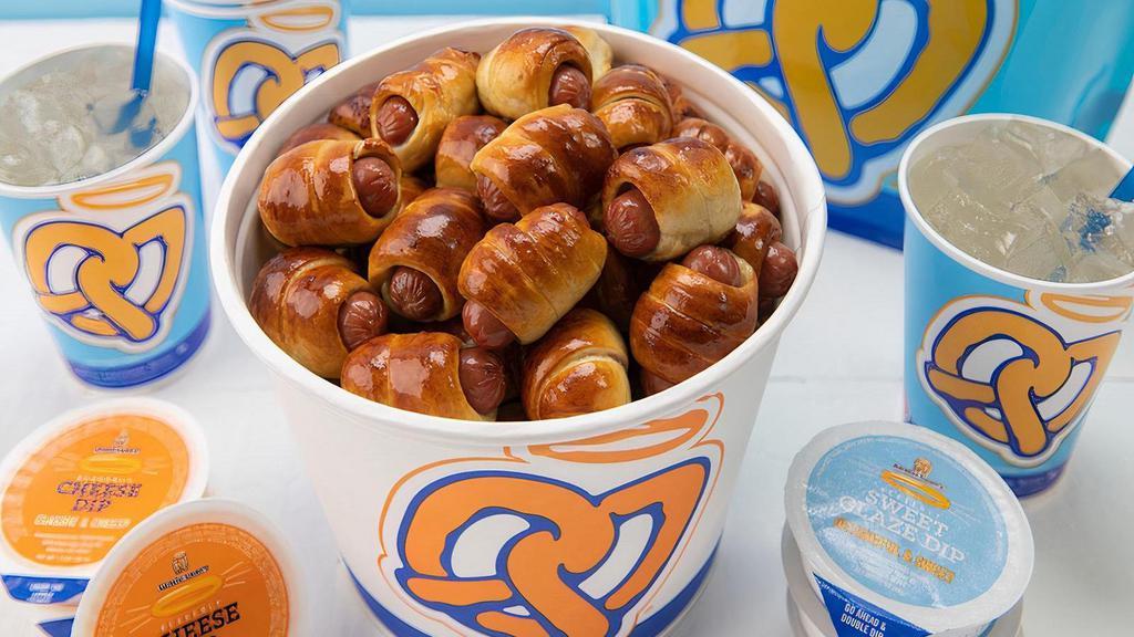 Mini Dogs Bucket Snack Pack · The perfect snack for 4-6 people. . You get a bucket filled with Mini Pretzel Dogs (50 pieces), 6 dips of your choice, and 1 gallon (approx. 6 cups of drink) of Original Lemonade or Lemonade Mixer in a flavor of your choice.