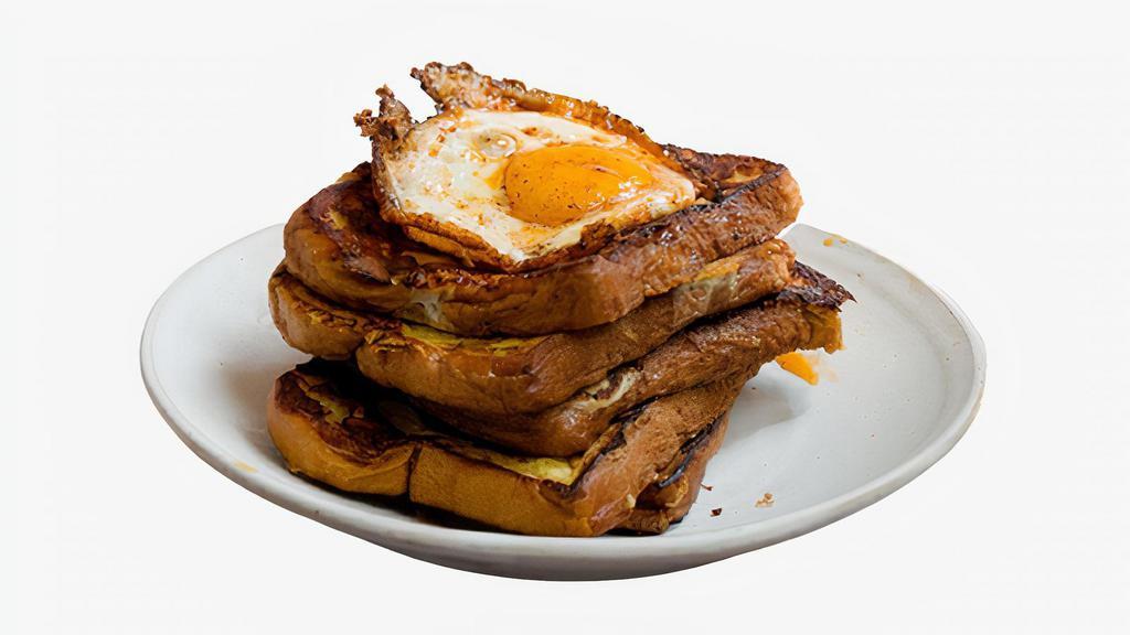 Savory French Toast · Two classic French toast topped with two fried eggs with syrup on the side.
