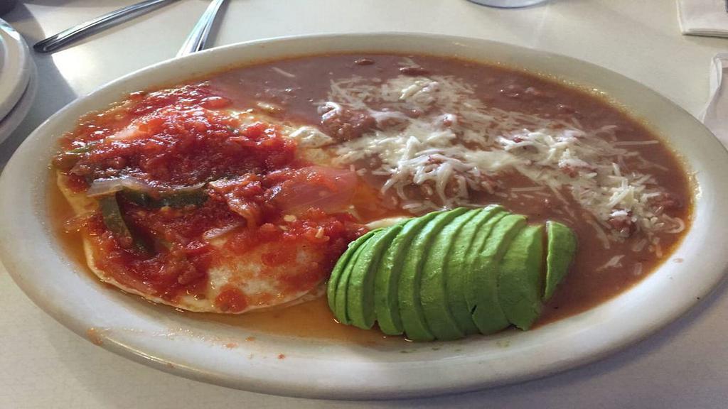 Huevos Ranchero · 2 Ranch eggs topped with spicy Spanish sauce, refried beans & tortillas.