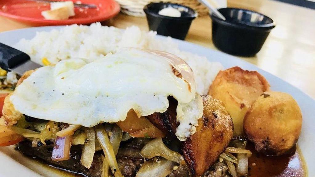 Lomo a Lo Pobre · Lean strips of beef sautéed with onions, tomatoes, French fries and special herbs. Topped with a fried plantain and fried egg. Served with rice.