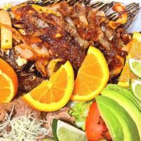 Mojarra Frita · Fried tilapia fish served with a side of rice and refried beans with a side salad and corn o...