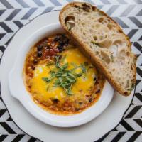 Spicy Baked Eggs · Two eggs, spicy tomato and black bean stew, cheddar cheese, cilantro, toast