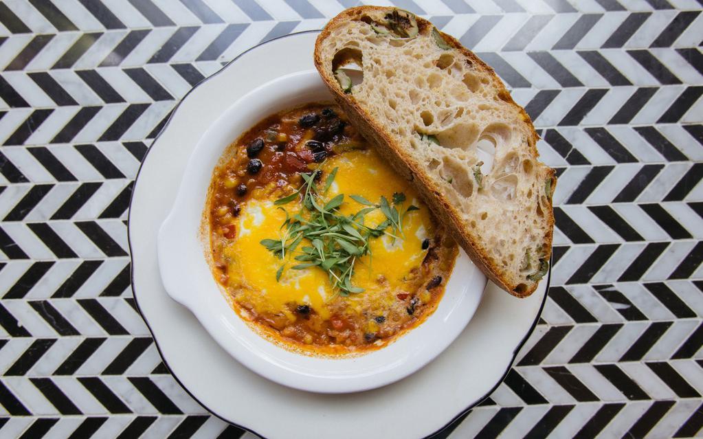 Spicy Baked Eggs · Two eggs, spicy tomato and black bean stew, cheddar cheese, cilantro, toast