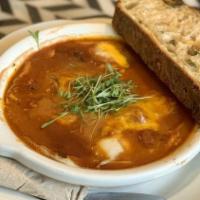 Spicy Baked Eggs · Two eggs, spicy tomato and black bean stew, cheddar, cilantro, olive toast.
