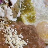 Chilaquiles Con Huevos · Tortilla chips, scrambled eggs with red or green sauce on top, cotija cheese, cilantro & oni...