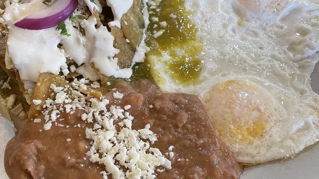 Chilaquiles Con Huevos · Tortilla chips, scrambled eggs with red or green sauce on top, cotija cheese, cilantro & onion.