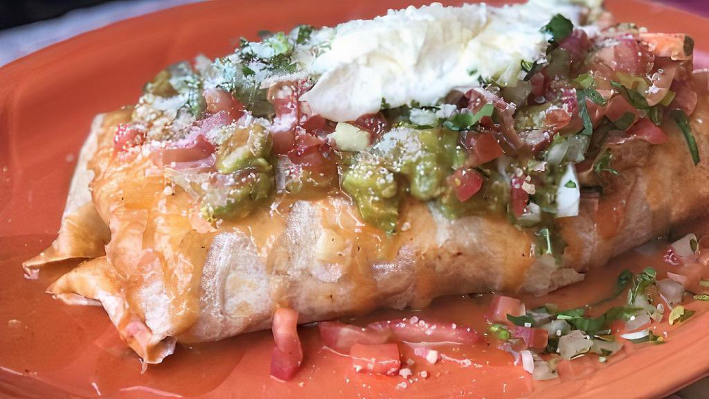 Macho Burrito · inside: refried beans, cheese, rice and choice of meat
topped with: burrito sauce, guacamole, sour cream, cilantro, onions, tomatoes, and cotija cheese.