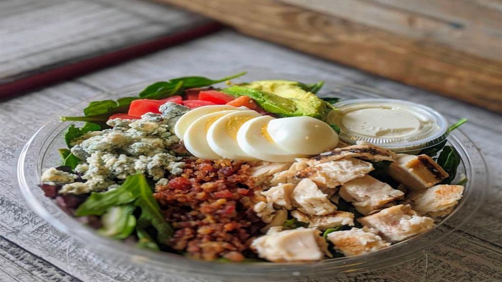 Cobb Salad · Chopped Romaine and Spring Mix, Cherry Tomatoes, Crisp Bacon, Sliced Hard-boiled Egg, Avocado, Grilled Chicken, Crumbled Blue Cheese and Blue Cheese Dressing. Served with Sourdough Bread.