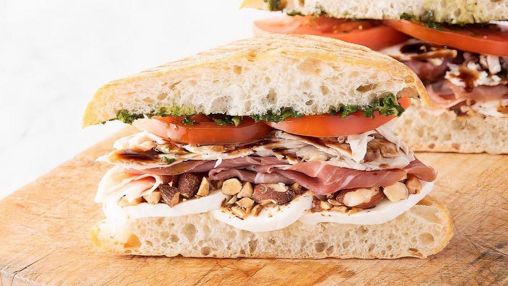 Prosciutto & Chicken Sandwich · prosciutto & roasted chicken breast with fresh mozzarella, crushed honey roasted almonds, basil pesto, balsamic glaze drizzle, tomatoes (580 cal) on panini-pressed ciabatta (260 cal). can be requested gluten free by selecting the gf bread option