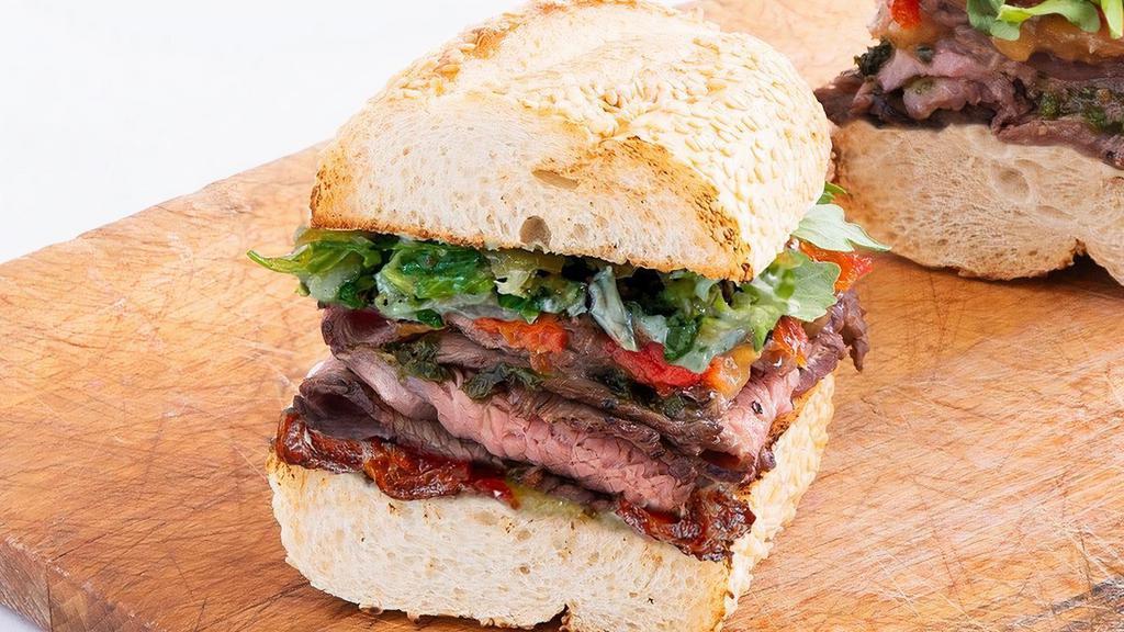 1/2 Chimichurri Steak & Bacon · roasted, carved steak and Applewood smoked bacon topped with marinated red peppers, caramelized onion jam, chimichurri, shredded romaine, herb aioli (640) on a toasted sesame roll (300)