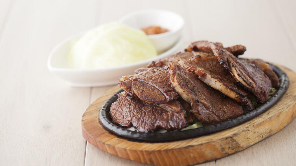 Beef Short Ribs · Served with steamed cabbage wrap, side dishes, and rice.