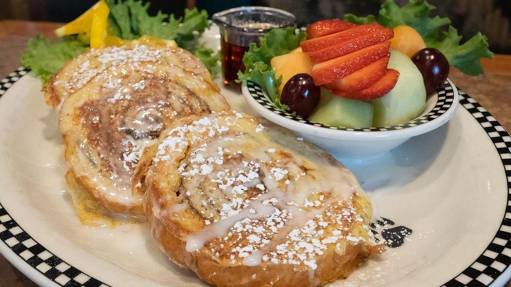 Cinnamon Roll French Toast · 3 slices of thick-cut cinnamon roll dipped in French toast batter and grilled then topped with powdered sugar and drizzled with icing. Served with fresh fruit.
