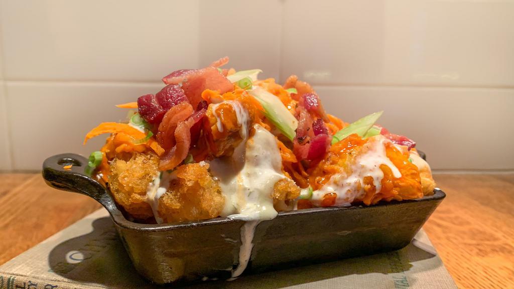 Buffalo Chicken Tots · Crispy tots topped with three cheese sauce, bleu cheese dressing, crispy buffalo chicken pieces, bacon bits, shredded carrots, and green onions.