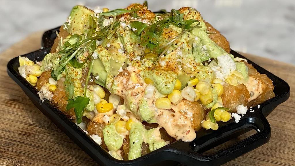Elote Tots · crispy tots topped with 3-cheese sauce, chipotle ranch, roasted corn, avocado, cilantro crema, cilantro, and dusting of cayenne