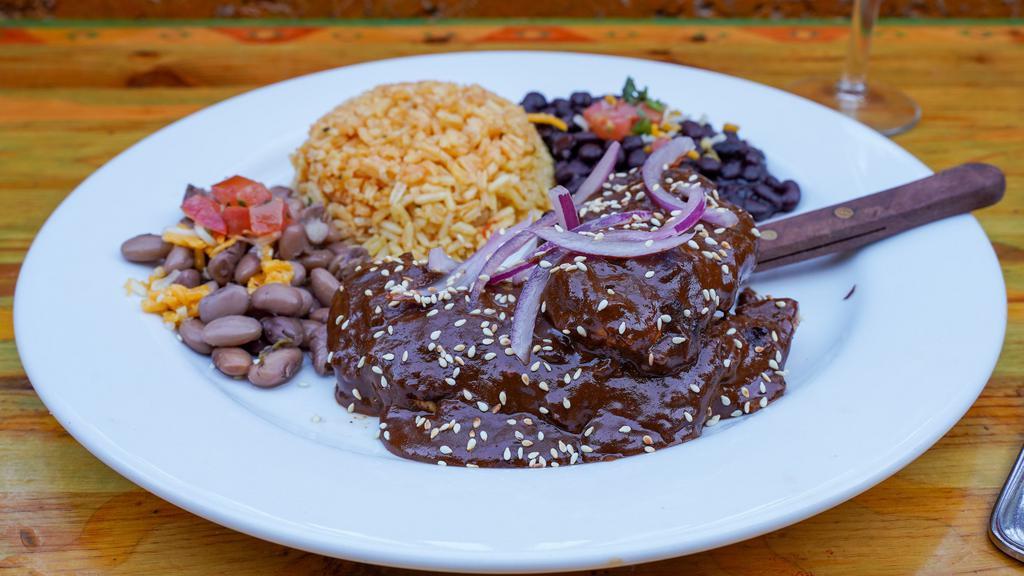 Chicken Mole Plate · Tender grilled chicken breast smothered in mole sauce, topped with lime pickled onion and ajonjoli. Served with rice and choice of black or pinto beans.