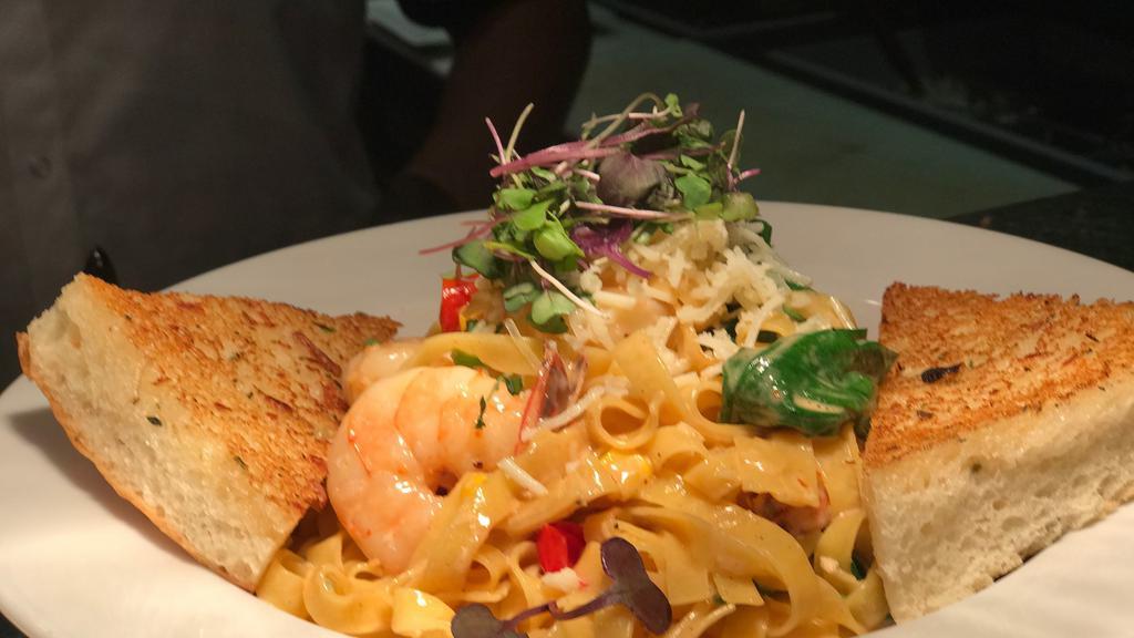 Prawn Pasta · Fettuccine pasta with prawns, tomatoes, corn and spinach, tossed in a chipotle cream sauce and served with garlic bread.