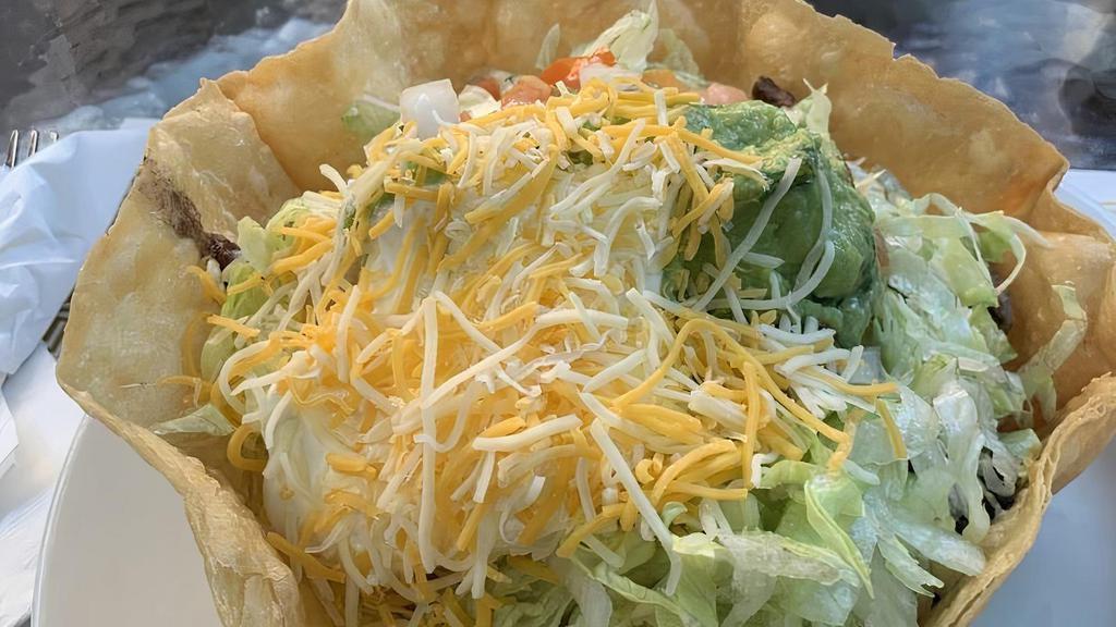 Fiesta Tostada Salad · A flour tortilla shell served with steak beef or chicken, sautéed onions, rice, iceberg lettuce, guacamole, salsa fresca, sour cream, and choice of beans, topped with cheese.