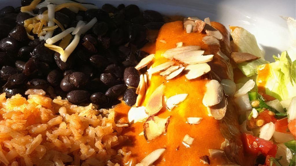 Enchiladas Guajillo · Two corn tortillas filled with meat or cheese and topped with Guajillo sauce and sliced almonds.