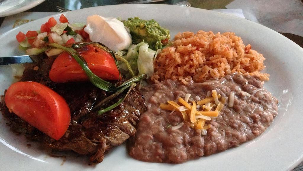 Carne Asada · Rib eye steak served with guacamole, sour cream, salsa fresca, green onions, and tomatoes with flour tortillas.
