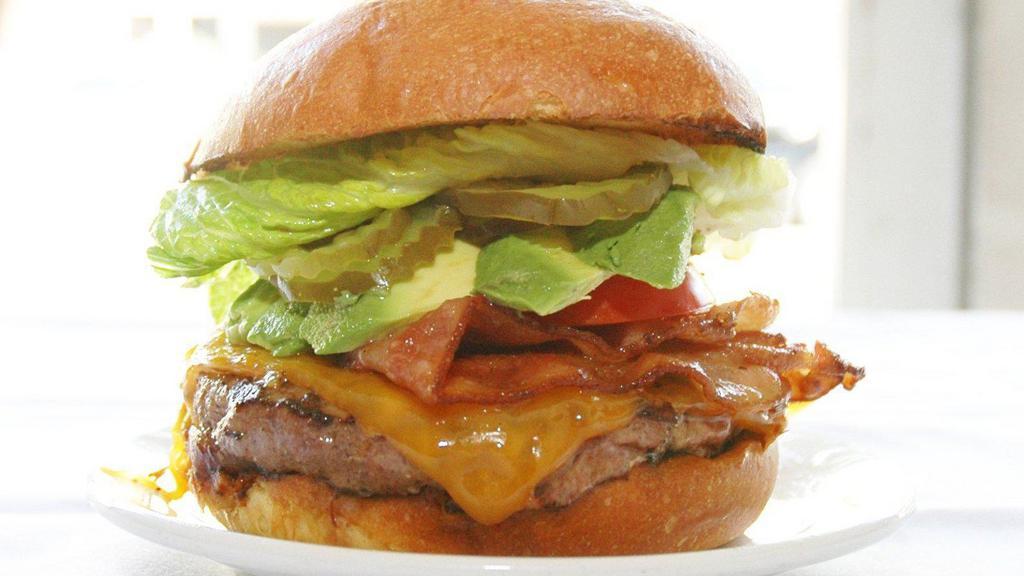 The New York Burger · Bacon, Cheddar cheese and avocado served on a perfect brioche bun with caramelized onions, chipotle remoulade, pickles, tomato and lettuce. Add small fries with curry ketchup for an extra charge.