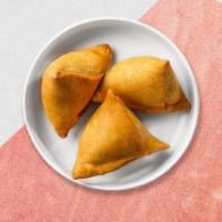 Vegetable Samosa · Two crispy puffs stuffed with potatoes and green peas fried in a crispy wheat layer.