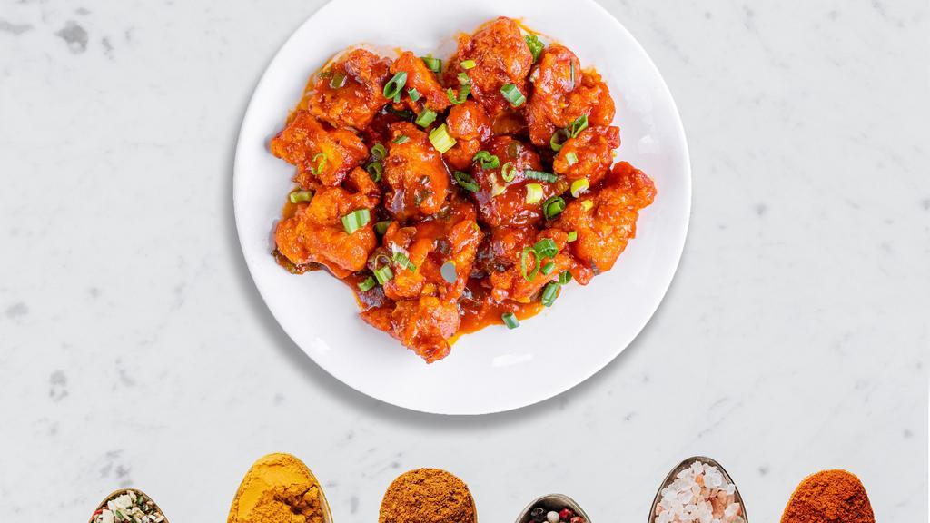 Cluck With Manchurian · Crispy chicken balls cooked in a spicy gravy. Garnished with spring onions.