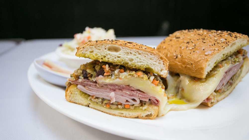 Muffuletta · A New Orleans classic: Ham, Salami, Mortadella, Swiss, Provolone & Mozzarella piled on a toasted seeded roll and dressed with house olive salad. Choice of potato salad or cole slaw side.