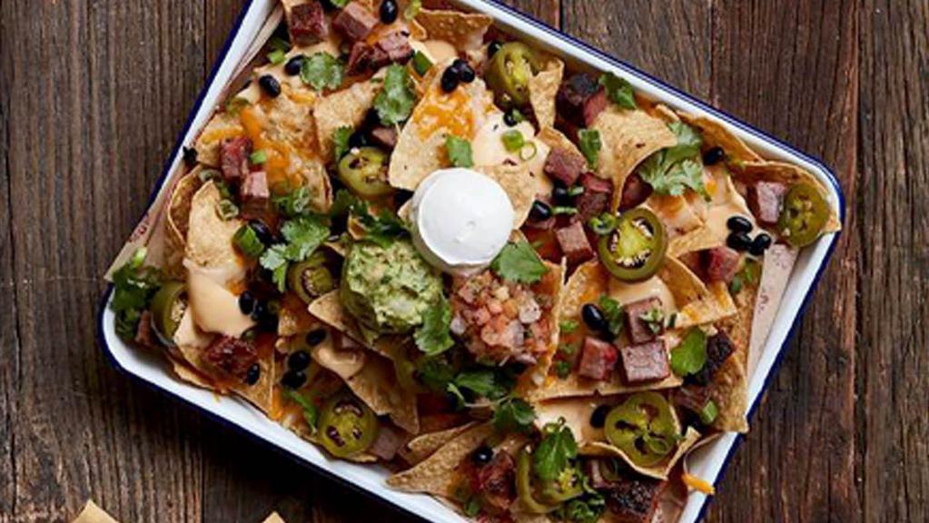 SMOKED BBQ NACHOS · Lucille's Favorite!. Crisp tortilla chips layered with melted cheese, black beans, smoked jalapeños, sour cream, fresh salsa and guacamole. Piled high with your choice of smoked brisket, smoked chicken, or pulled pork.