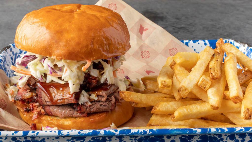 Texas-Style Brisket Sandwich · Slices of slow-smoked brisket, hand-carved to order, drizzled with our original BBQ sauce, topped with creamy coleslaw on a soft brioche bun.