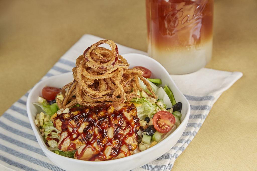 BBQ CHICKEN SALAD · Grilled chicken breast on a bed of fresh greens, BBQ ranch dressing, tomatoes, grilled sweet corn, cucumbers, black beans, cheddar cheese, topped with onion straws. Dressing served on the side.