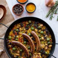 Paella Marroquí · harissa chicken, merguez sausage, almonds, raisins, olives, tomato-onion sofrito, saffron, b...